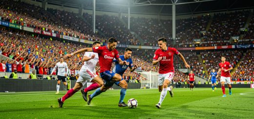 Stade de football international rempli de spectateurs, avec des joueurs en action sur une pelouse éclairée pendant un match de grande compétition.